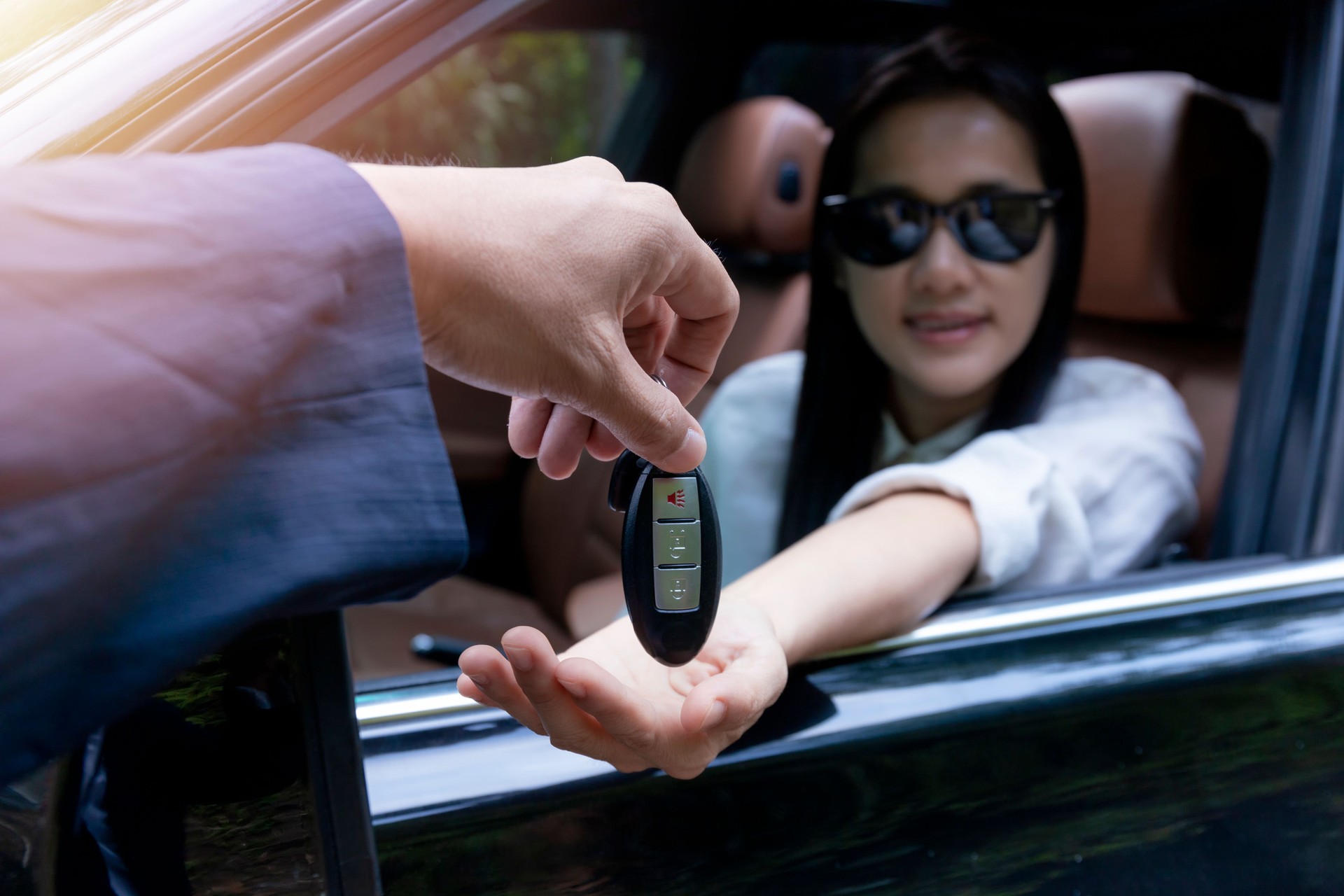 Fermez-vous vers le haut du concessionnaire donnant la clé à la nouvelle voiture de propriétaire. Nouvelle voiture. Concessionnaire automatique donnant la clé d’automobile de femme pour l’essai routier sur la route de campagne. Les femmes souriante